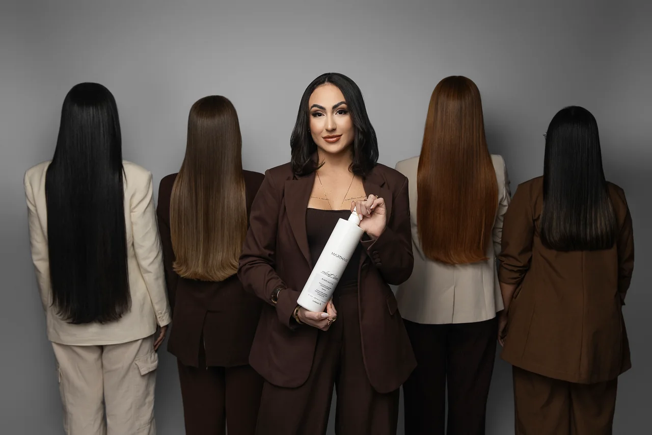 Luanna Martins segurando um produto Marthair, entre duas mulheres com cabelos lisos vistos de costas